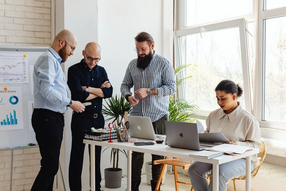 Teammitglieder besprechen eine Aufgabe an Arbeitsplätzen im hellen Büro.