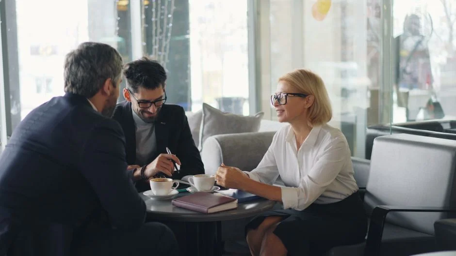 Drei Personen besprechen Unterlagen bei einem Geschäftstermin