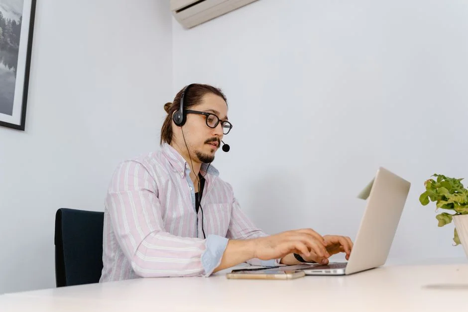 Mitarbeiter mit Headset arbeitet an einem Laptop.