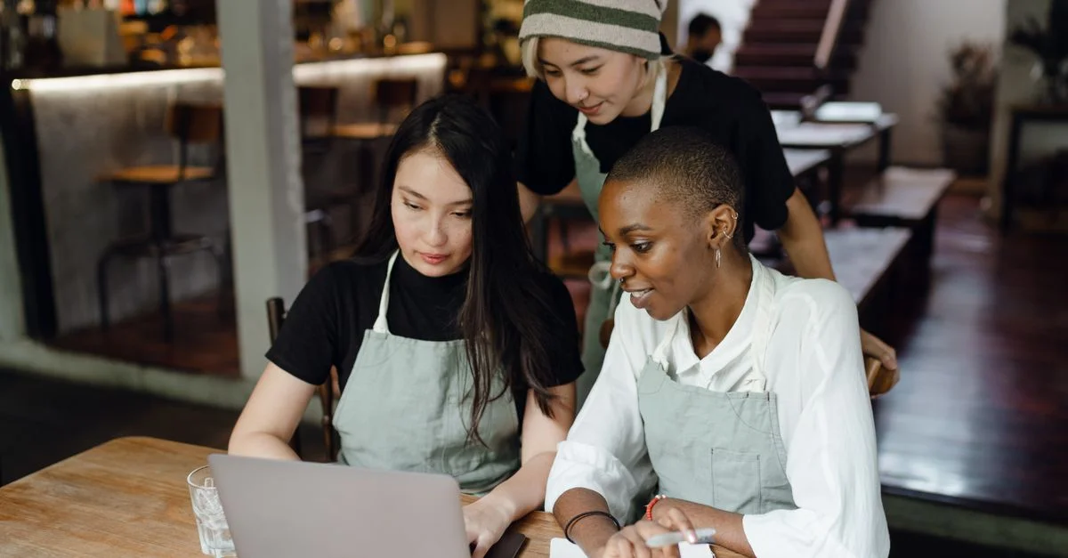 Zwei Kolleginnen arbeiten in einem Café gemeinsam am Laptop