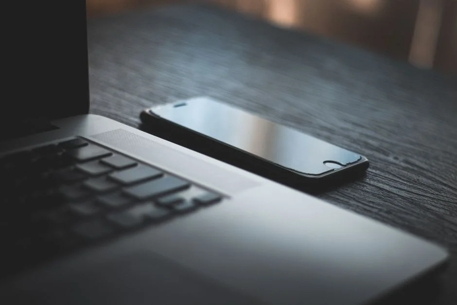 Smartphone liegt neben einem Laptop auf einem Schreibtisch