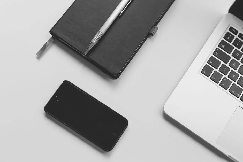 Smartphone, Notizbuch und Laptop liegen auf einem Arbeitstisch