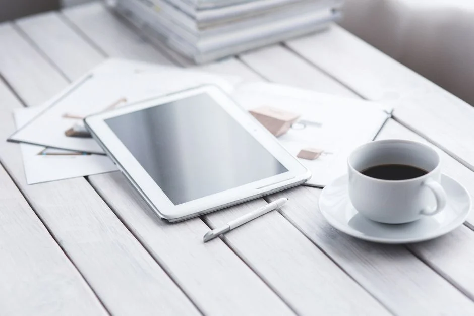 Tablet und Kaffeetasse auf einem hellen Schreibtisch