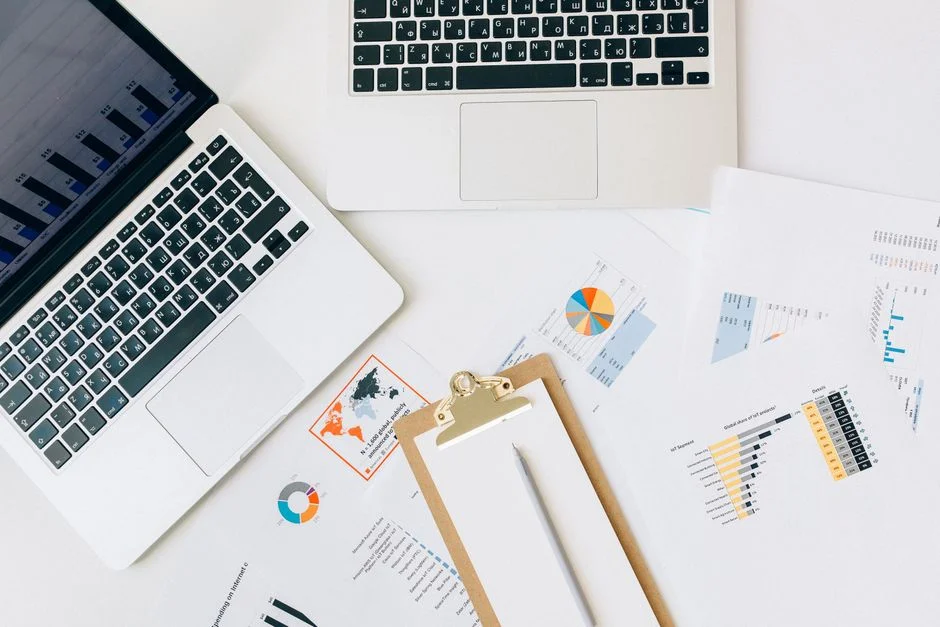 Laptops, Diagramme und eine Checkliste liegen auf einem Schreibtisch
