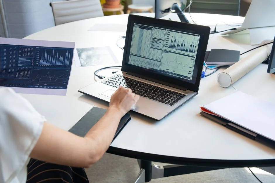 Laptop und Ausdrucke mit neutralen Diagrammen auf einem Schreibtisch
