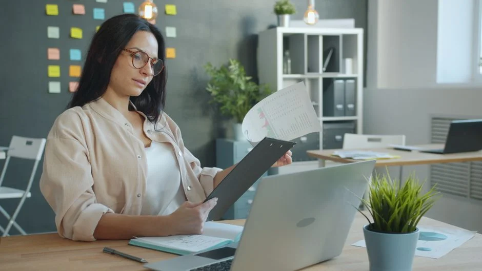 Unternehmerin liest an ihrem Schreibtisch eine ausgedruckte Auswertung durch