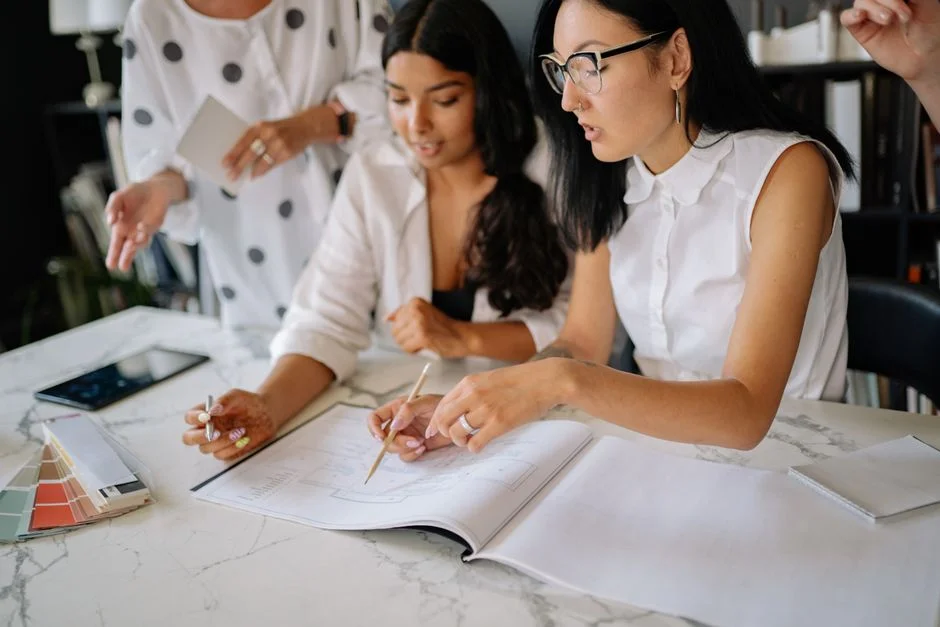 Drei Frauen besprechen Unterlagen und Materialproben an einem Tisch