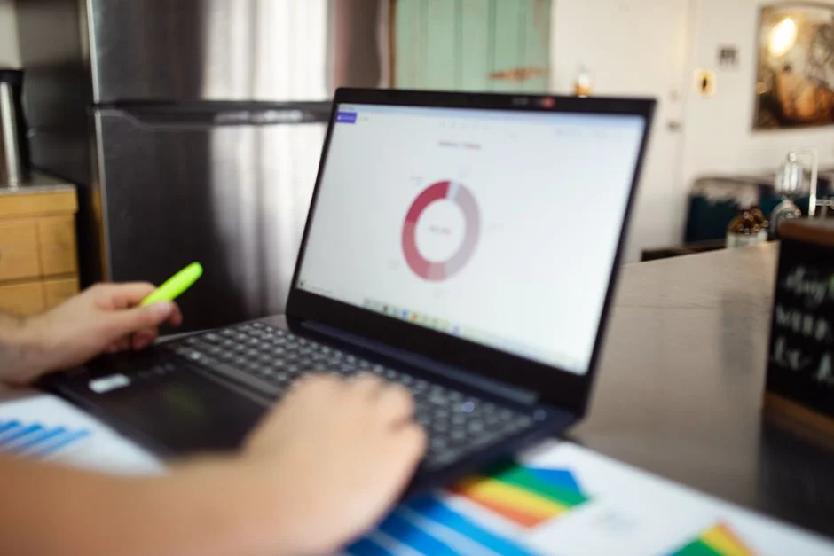 Hand markiert ein Diagramm auf einem Laptop
