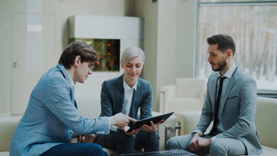 Drei Personen besprechen gemeinsam Unterlagen und ein Tablet