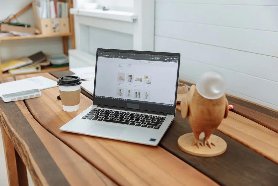 Laptop auf einem Holzschreibtisch zeigt eine Website-Ansicht neben einer Kaffeetasse