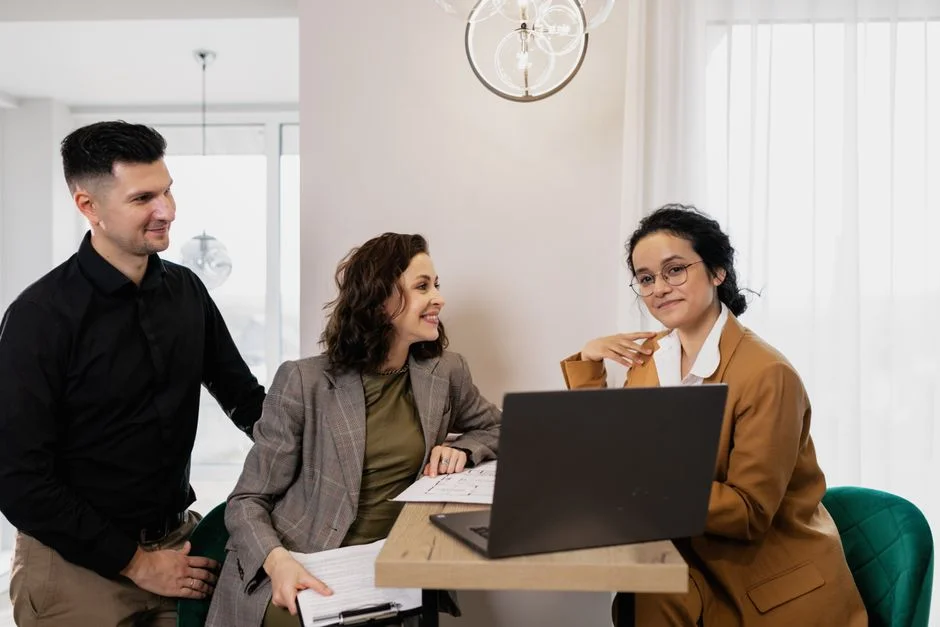 Berater und zwei Kundinnen besprechen gemeinsam Unterlagen am Laptop